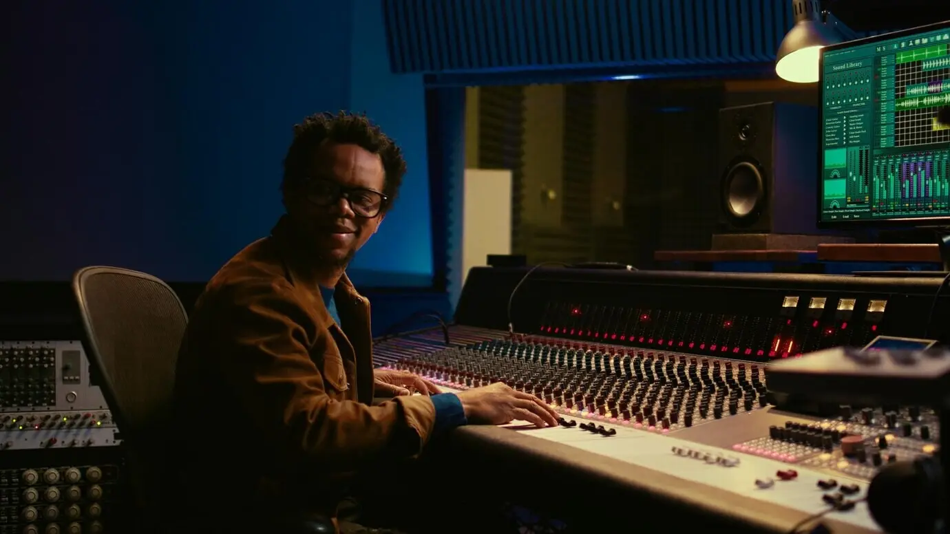 Музыкальный продюсер управляет микшерным пультом в контрольной комнате.