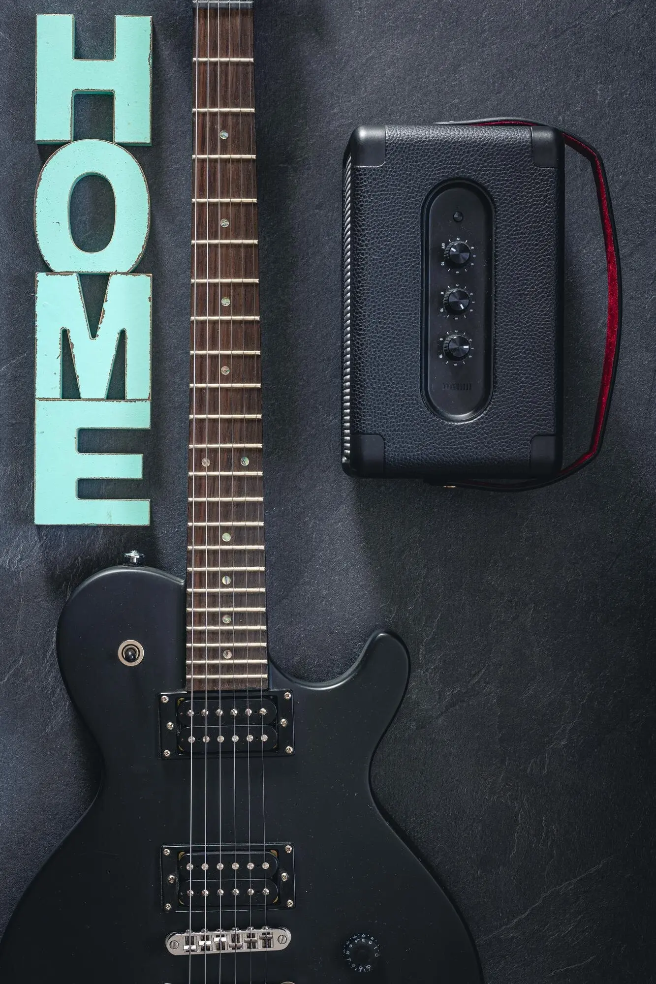 На темном фоне изображены электрогитара и усилитель, присутствует декоративное слово «home».
